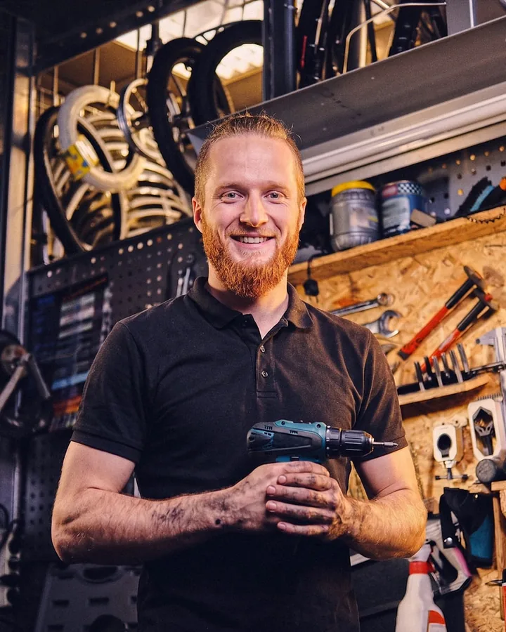 A bike mechanic smiling in his workshop